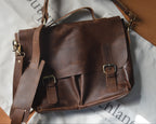 Brown leather satchel bag on a white surface with visible branding.
