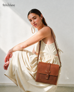 Woman holding a brown leather bag against a white background with 'Stitchlane' branding.